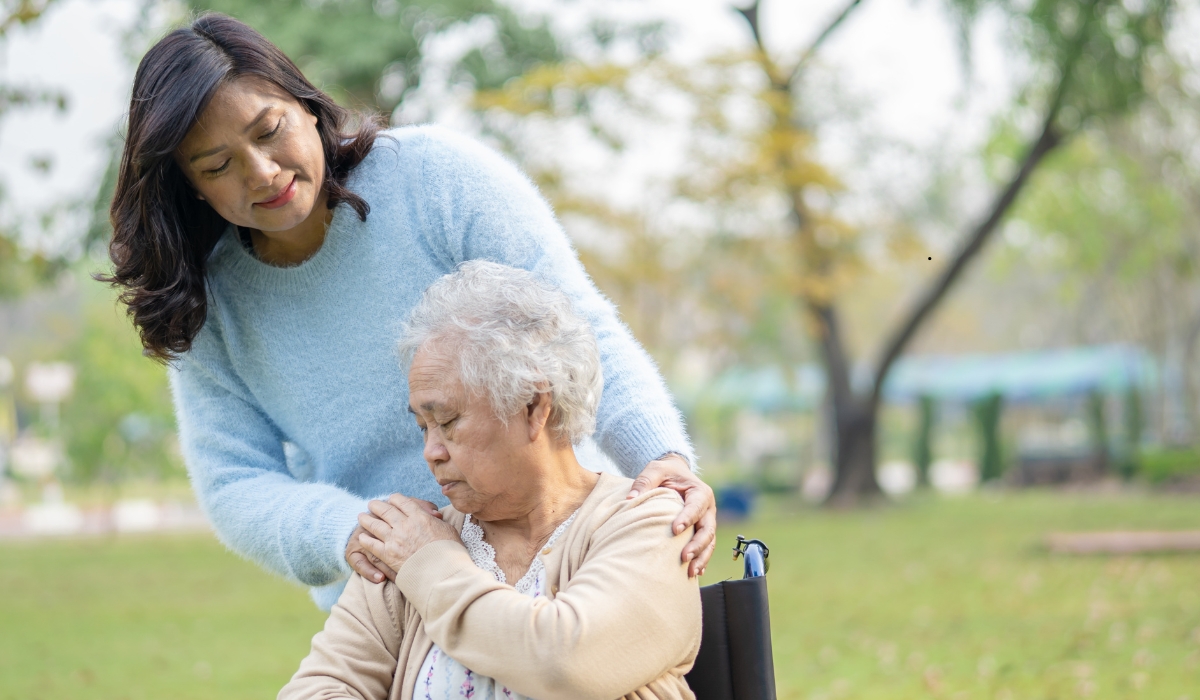 Elderly caregiver assisting a senior woman with mobility exercises in a bright and comfortable care facility