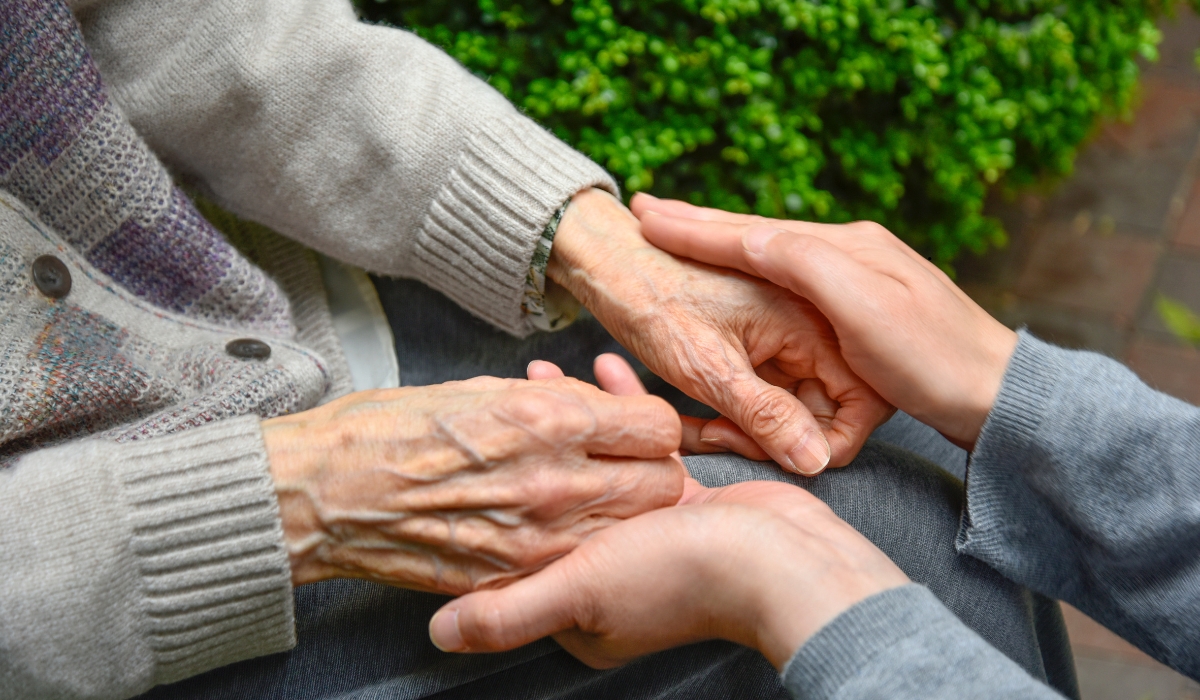 A compassionate caregiver assisting an elderly woman with daily activities in a warm, comfortable home environment.